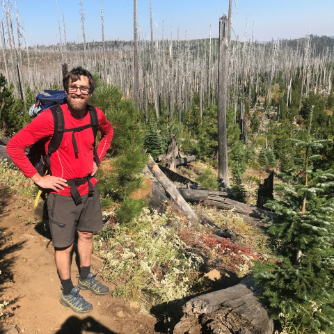 NWFSC PI Matthew Reilly in a natural landscape with burned trees
